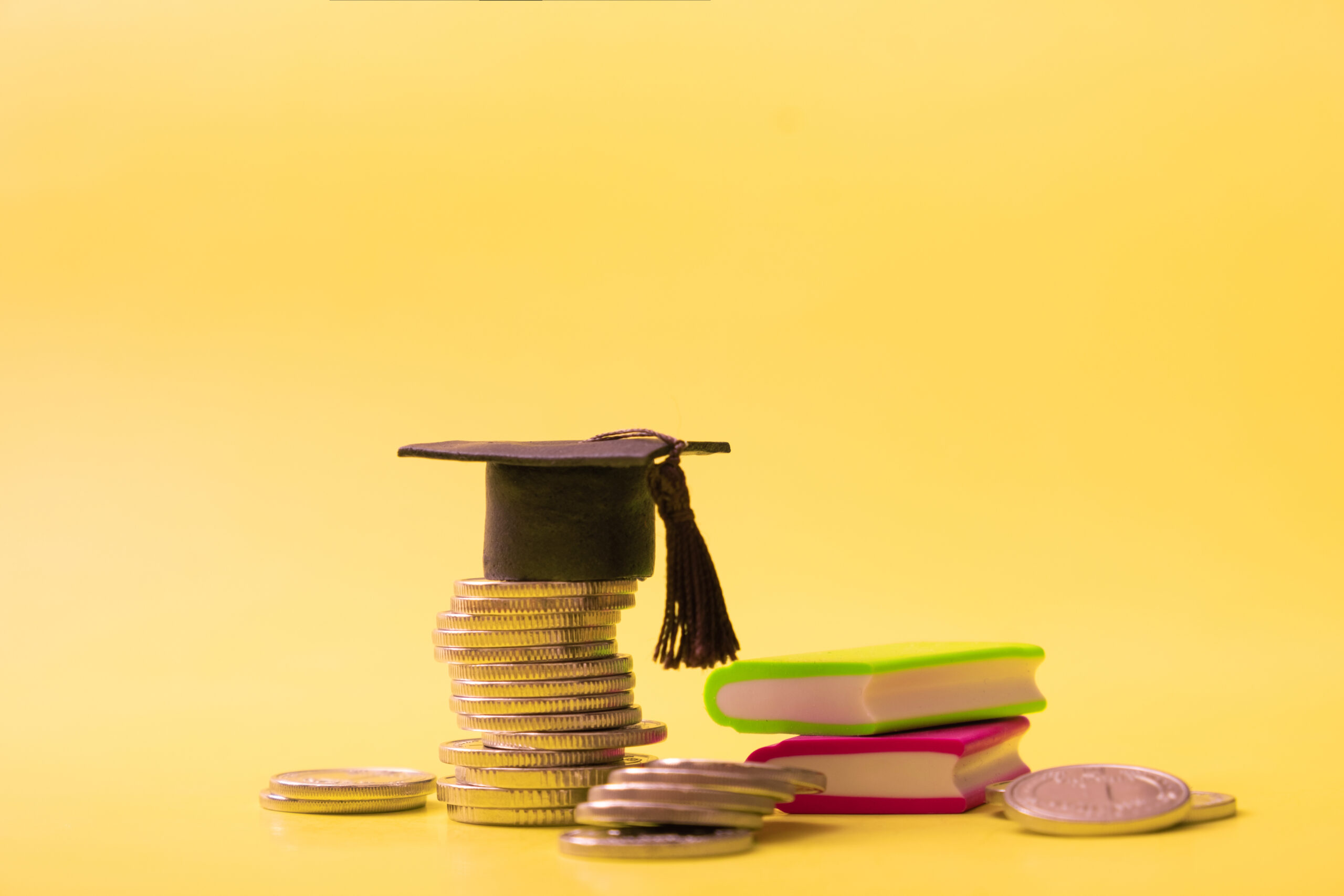 graduated cap with coins and books on yellow backg 2024 07 21 17 04 09 utc