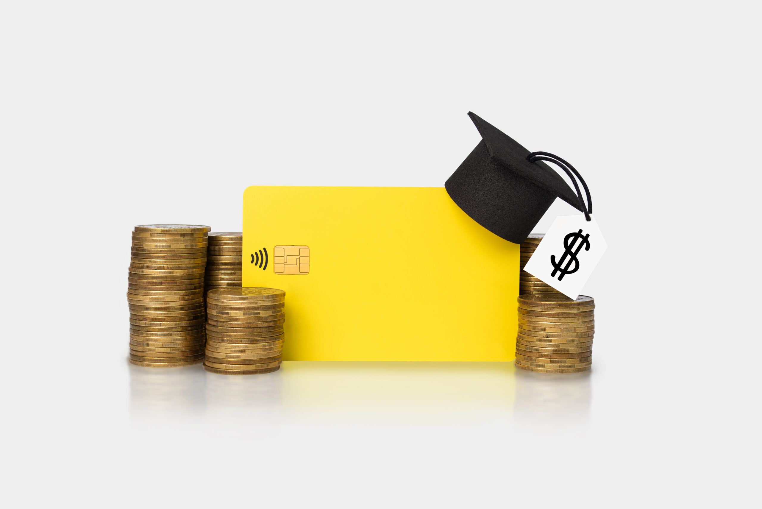 Concept of financial literacy and education. Bank card and graduation hat on gold coins. Economy of finances.