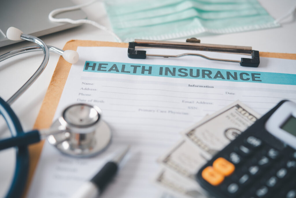 Stethoscope and calculator placed on health insurance documents,