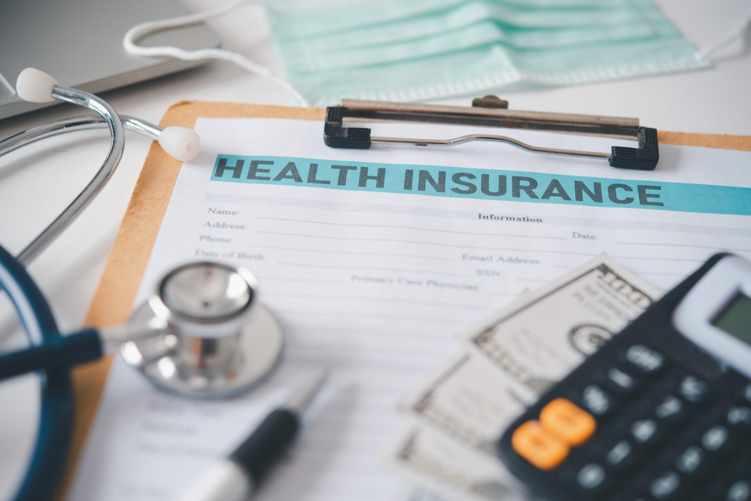 Stethoscope and calculator placed on health insurance documents,