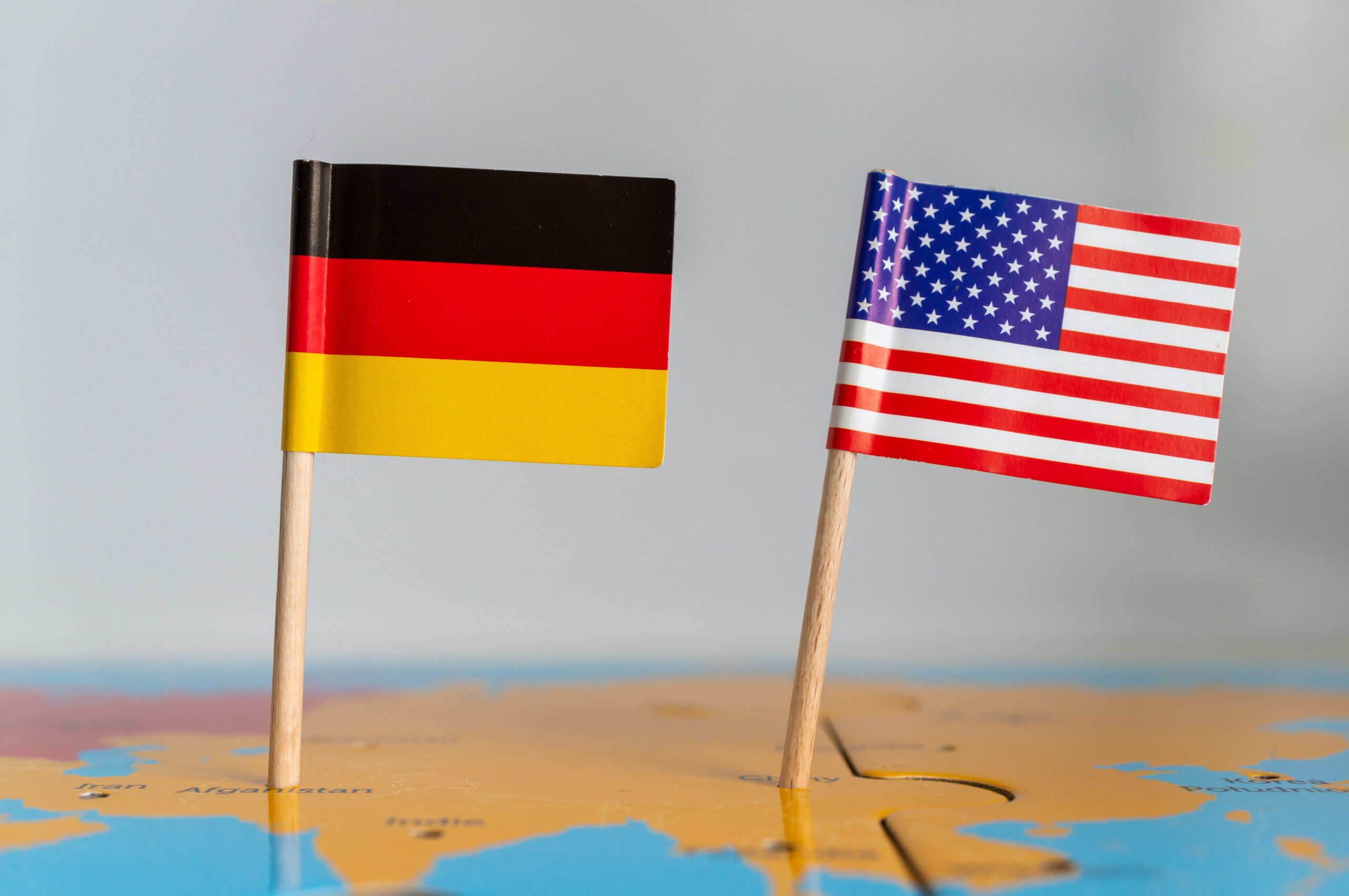 Small flags of Germany and the USA on a wooden stick fixed on the globe